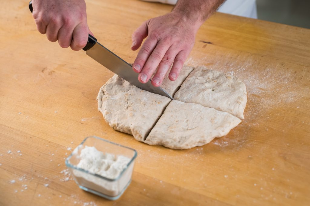 Cortamos la masa de la elaboración de los panecillos de semillas en trozos